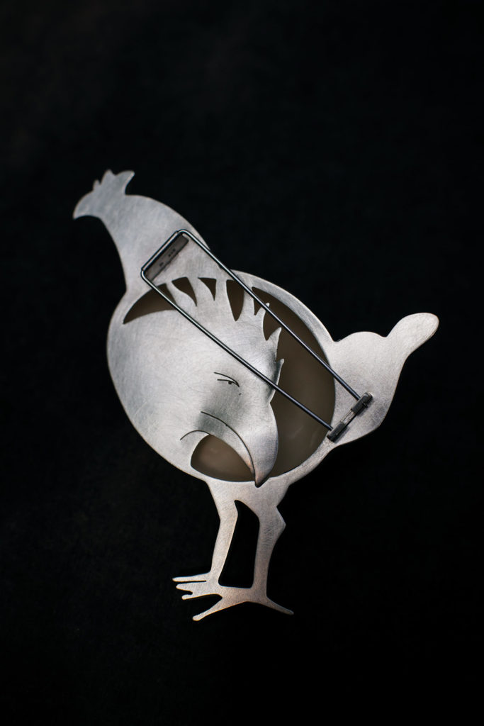 Rückseite der Brosche <em>Legehenne, die Henne bedauert ihr Schicksal</em>