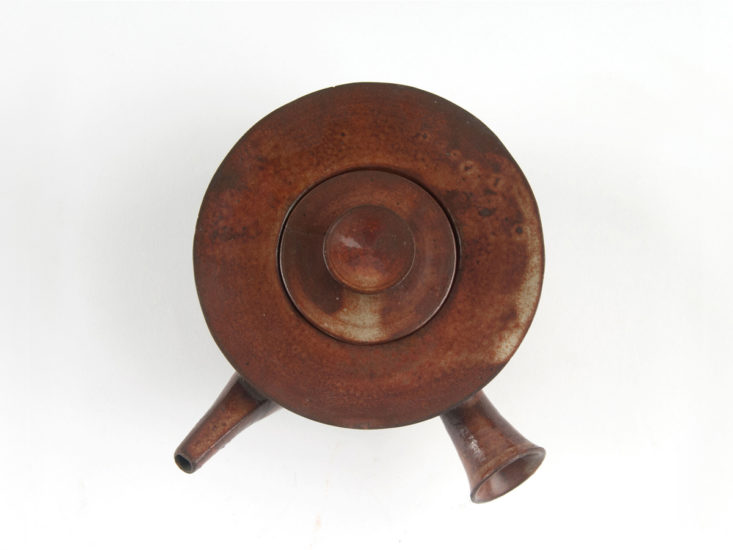 Die Teekanne ist aus dunkelbraunem Steinzeug auf Beige gefertigt.